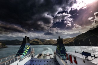 View of clouds and mountains on water from the stern of a ferry, Queen Charlotte Sound,