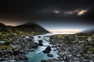 Dark mountain landscape with a narrow river surrounded by boulders in the evening light, Hooker