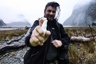 Man wearing outdoor clothes with mosquito repellent and head net in foggy mountain backdrop,