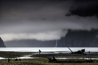 Dramatic clouds and fog over the water in Milford Sound, with dark-framed mountains, zero
