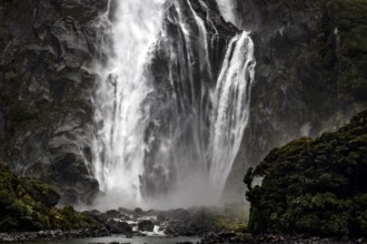 Powerful waterfall falls over rocks, creating an impressive spray, Milford Sound, New Zealand