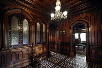 Antique foyer with intricate wood ornaments and a chandelier, Larnach Castle, Otago Peninsula, New