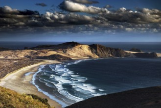 Dramatic coastal landscape with sweeping beaches and wild waves under a cloudy sky, Cape Reinga,