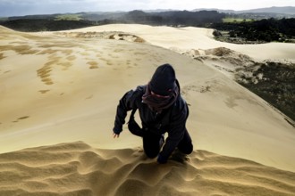 Person fighting his way through sandy dune landscape in stormy weather