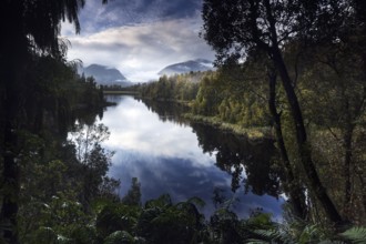 Lake Matheson offers a tranquil reflection of the surrounding mountains and forests in soft morning