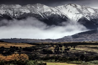 Snow-capped mountains with extensive pasture and fog, Milford Road, New Zealand