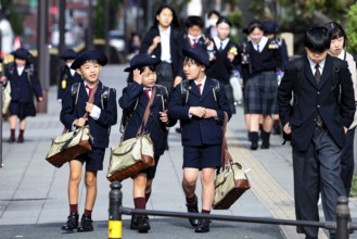 Group of schoolchildren wearing uniforms on a busy sidewalk in Osaka, Osaka, Japan