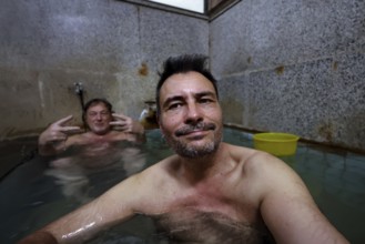 Two men relax in a traditional hot spring bath, Yamanouchi, Japan