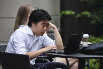 A salariman concentrates on a laptop outdoors, Tokyo, Hamamatsucho, Japan