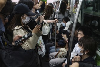 Passengers on a full train, many wearing masks, Tokyo, Japan