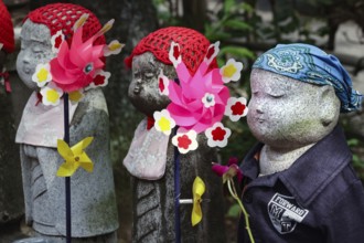 Row of jizo statues with colorful wind turbines at Zojo-ji Shrine in Minato, Tokyo, Tokyo, Japan
