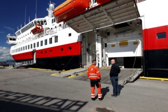 Hurtigruten ship at Hurtigrutenkai in Hammerfest with open cargo hatch and two people on the quay,