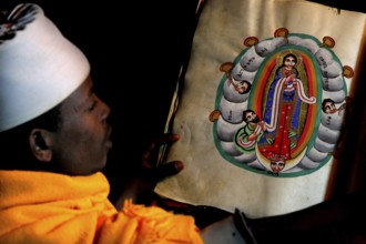 Abba Philippos is studying an artfully illustrated manuscript in the monastery church, Debre Damo,