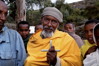 A pilgrim with a cross surrounded by other believers at Debre Libanos, Debre Libanos, Ethiopia