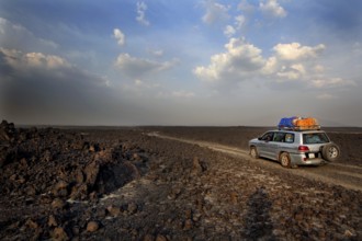 Landcruiser drives through the lava desert under a dramatic sky, zero