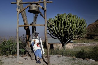 Priest next to a bell near the rock church Debre Mariam Krokor, zero