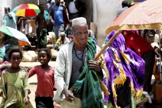 Lively market in Harar with people wearing traditional robes and colorful umbrellas, Harar, Oromia,