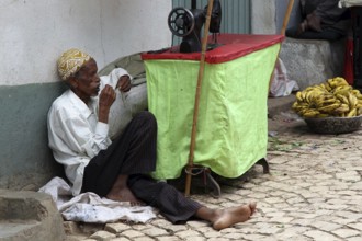 Tailor in Harar works quietly on the street surrounded by bananas, Harar, Oromia, Ethiopia