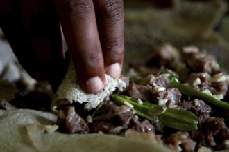 Hand grabs Injerra with tibs during an Easter meal, Lalibela, Amhara, Ethiopia