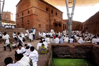 People wearing white clothes gather in front of the Bete Maryam rock church, Lalibela, Amhara,