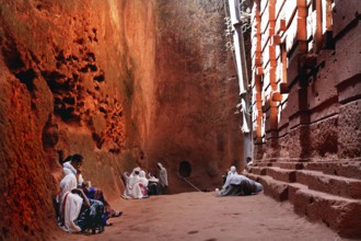 People wearing traditional clothing sit at Bete Emanuel, impressive rock architecture, Lalibela,