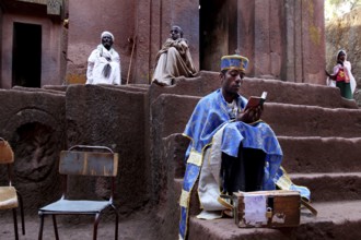 A priest reads in front of the rock church of Bete Gyorgis in Lalibela, Lalibela, Amhara, Ethiopia