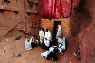 Believers gather in front of the Bete Abba Libanos church under a red cloth, Lalibela, Amhara,
