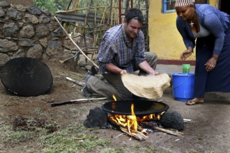 Roland and Worknesh prepare injera together on a fireplace, Lalibela, Ethiopia