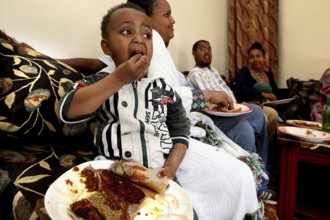 A child eats joyfully during a traditional Easter meal, Lalibela, Ethiopia