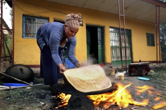 Worknesh prepares injera over an open fire pit, Lalibela, Ethiopia