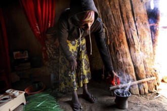 Lady carefully performs the coffee ceremony in her cozy abode. Smoke rises, Lalibela, Amhara,