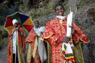 Priest in traditional red robes and colorful umbrella, Lalibela, Lasta Mountains, Ethiopia
