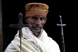 Priest with crosses and traditional clothing against black background, Lalibela, Lasta Mountains,