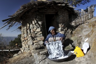 Woman washing in front of a traditional round hut with picturesque views of Lasta Mountains,