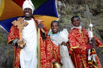Three priests in magnificent robes with colorful umbrellas, Lalibela, Lasta Mountains, Ethiopia