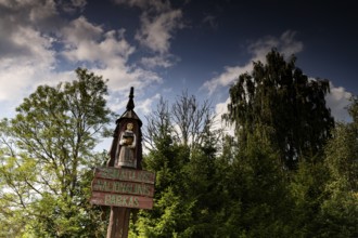 Entrance sign with carved figure in front of trees in Zemaitija National Park, Zemaitija National