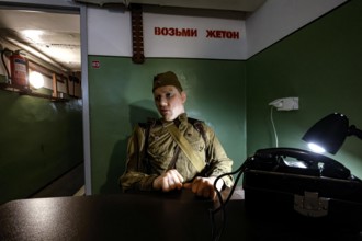 A person in military uniform sits in an atmospherically lit bunker in Plokstine, Plokštine, Telšiai