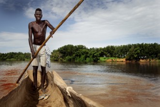 Man navigates in a dugout along the Omo River, surrounded by thick vegetation, Omorate, Ethiopia