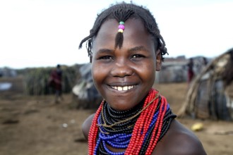 Young woman with colorful necklaces smiles in a Dessanech village, Omorate, Ethiopia