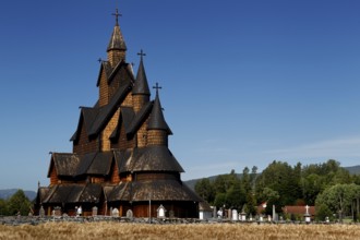 Historic stave church in Heddal with ornate wooden structure and blue sky in the background,
