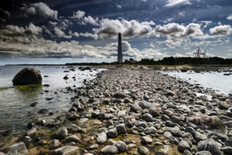 A lighthouse with rocky coastline under a dramatic sky in Tahkuna, Hiiumaa, Tahkuna, Estonia