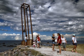 Group of people at a memorial on the coast under dramatic sky, Tahkuna, Hiiumaa, Estonia