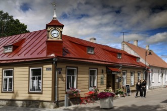 Historic building with red roof in the old town, people walking along the street, Kuressaare,