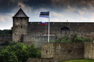 Close-up of Hermann Fortress with Estonian and Russian flags including dramatic clouds, Narva,
