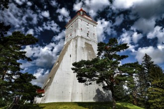 Powerful Köpu lighthouse surrounded by trees and clouds, Hiiumaa, Köpu, Estonia
