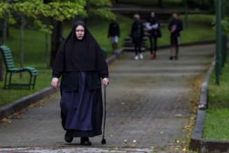 Nun with walking stick walks through the park in Kuremäe, Kuremäe, Pühtitsa, Estonia