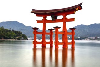 Red torii of Itsukushima Shrine stands in calm water, Miyajima, Japan