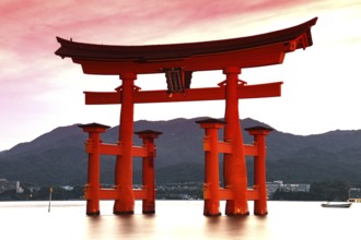 Illuminated torii of Itsukushima Shrine in water at night, Miyajima, Japan