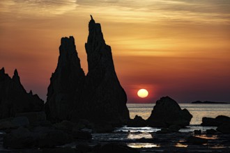 Sublime rock formations at sunrise silhouetting against the orange sky, Kushimoto, Japan