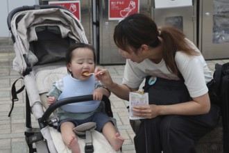 A mother feeds her child at a rest stop in Nagasaki, Nagasaki, Japan